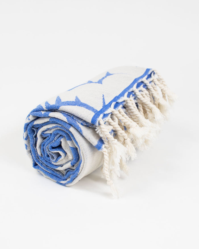 A blue and white Cognitive Surplus Cloud Watching Turkish Towel with fringes.