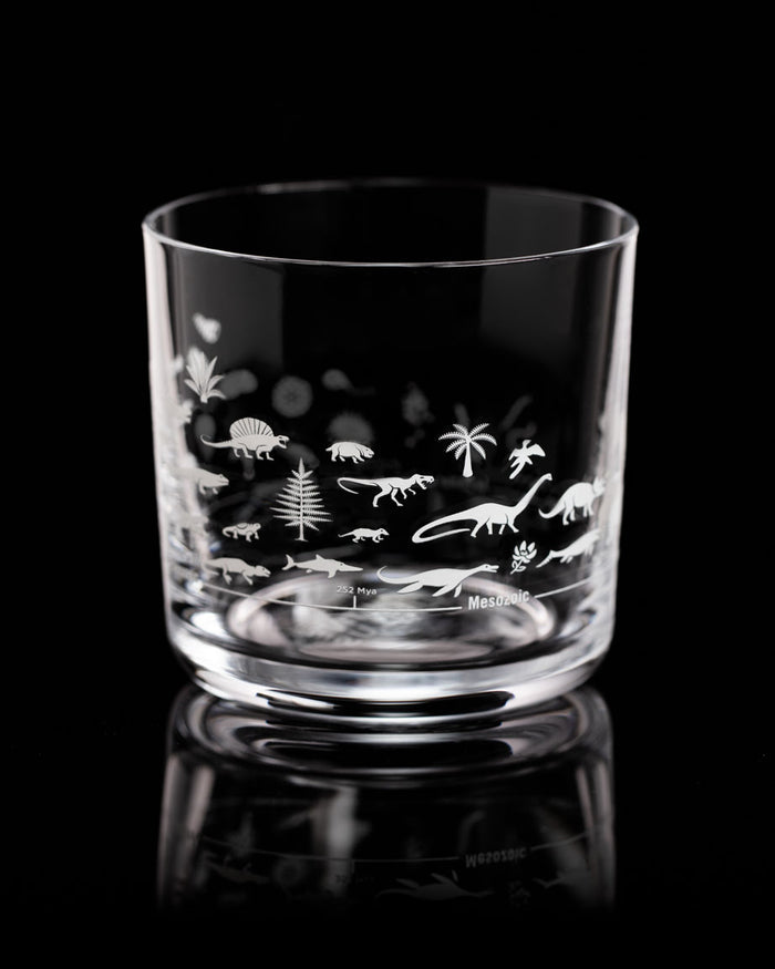 A Cognitive Surplus Geologic Time Scale Whiskey Glass with a design of dinosaurs on it.