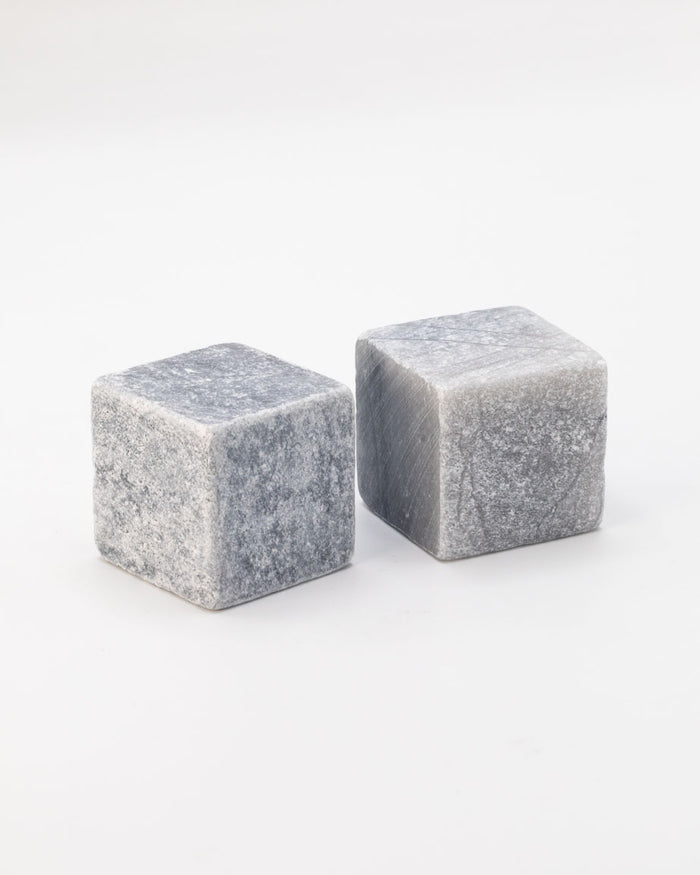 Two Mega Rocks Soapstone Whiskey Stones cubes on a white surface.