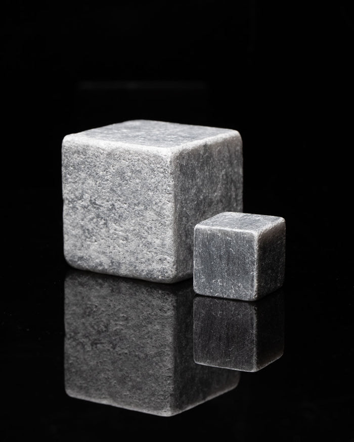 Two Mega Rocks Soapstone Whiskey Stones on a black surface.